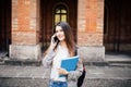 Gorgeous happy student holding notebooks speak phone on campus at college Royalty Free Stock Photo