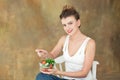 Gorgeous healthy woman sitting on a white chair eating a healthy salad from arugula, organic tomatoes.