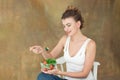 Gorgeous healthy woman sitting on a white chair eating a healthy salad from arugula, organic tomatoes.