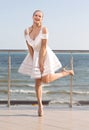 A gorgeous lady in fantastic white dress and on high heels on a hotel`s balcony. Royalty Free Stock Photo