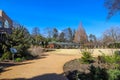 A gorgeous landscape in the garden with yellow winter grass, lush green trees and plants, bare winter trees with blue sky