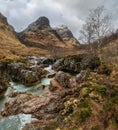 Gorgeous landscape image of vibrant River Coe flowing beneath snowcapped mountains in Scottish Highlands