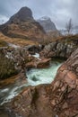 Gorgeous landscape image of vibrant River Coe flowing beneath snowcapped mountains in Scottish Highlands