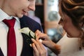 Gorgeous luxury blonde bride putting on boutonniere on the suit Royalty Free Stock Photo