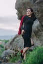 Gorgeous and luxury woman with black dress next to the huge ancient cliffs