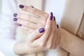 Gorgeous manicure, dark purple tender color nail polish, closeup photo. Female hands over simple background of casual clothes Royalty Free Stock Photo