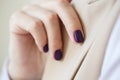 Gorgeous manicure, dark purple tender color nail polish, closeup photo. Female hands over simple background of casual clothes Royalty Free Stock Photo