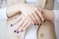 Gorgeous manicure, dark purple tender color nail polish, closeup photo. Female hands over simple background of casual clothes Royalty Free Stock Photo