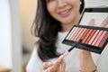 Gorgeous millennial Asian female beauty blogger reviewing an eye shadow palette Royalty Free Stock Photo