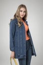 Gorgeous model posing in long blue denim jean coat and orange top