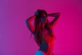 Gorgeous modern young model stylish woman in a sexy top with a perfect body straightens long hair and enjoys a bright neon red