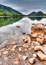 Gorgeous mountain lake with woodlands reflection and red rocks in the foreground Royalty Free Stock Photo