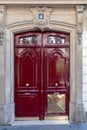 Gorgeous ornate burgundy red door of classical architecture stone house in Paris France. Polished red painted double door Royalty Free Stock Photo