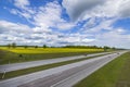 Gorgeous panoramic landscape view. Highway and green fields merging to blue sky with white clouds.