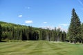 Gorgeous par 4 on a golf course surrounded by forest and big mountains in the background, on a beautiful sunny day in Kananaskis,