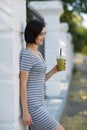 Beautiful woman with a green cocktail. A pretty woman leaning on a wall on a natural background. Casual fashion concept. Royalty Free Stock Photo