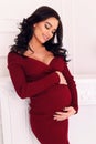 Gorgeous pregnant woman with long dark hair posing at bedroom Royalty Free Stock Photo