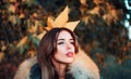 Gorgeous pretty woman in furry coat fallen leaf on head as crown. Trendy outfit. Her confidence is stunning. Woman