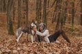 Gorgeous pretty woman in furry hat playing with dog in forest. Autumn mystical photoshoot. Concept of the power feminism