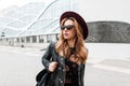 Gorgeous red-haired hipster young woman in dark sunglasses in an elegant hat in a stylish black leather jacket Royalty Free Stock Photo