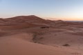 Gorgeous and scenic desert scene with the moon crescent high above beautiful sand dunes Erg Chebbi, Morocco, Merzouga Royalty Free Stock Photo