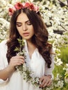 Gorgeous sensual woman with luxurious hair in elegant dress posing in blossom garden Royalty Free Stock Photo