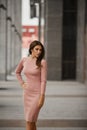 Gorgeous sexy busty woman with a perfect body, thin waist, and wide hips, in beige tight dress posing outdoors Royalty Free Stock Photo