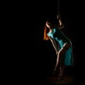 Gorgeous dancer in night club. woman in a long turquoise dress with a slit on a dark background. free space for