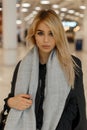 Gorgeous sexy young blonde with gray eyes with sexy lips in a stylish gray coat with a trendy scarf with a handbag stands Royalty Free Stock Photo