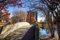 A gorgeous shot of an autumn landscape in the park with a stone bridge over the lake surrounded by gorgeous autumn colored trees