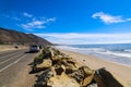 A gorgeous shot of the beach along the coast with vast blue ocean water, large rocks along the beach, silky sand with blue sky Royalty Free Stock Photo