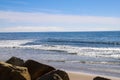 A gorgeous shot of the beach near a long stretch of road with cars and large rocks along the beach, vast blue ocean water