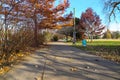 A gorgeous shot of a long smooth winding footpath in the park surrounded by gorgeous autumn colored trees with blue sky and clouds