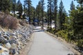 A gorgeous shot of a man walking down a smooth pathed hiking trail near the vast blue lake water Royalty Free Stock Photo