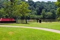 A gorgeous shot of the park with red benches surrounded by lush green trees reflecting off the Chattahoochee river water