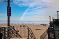 A gorgeous shot of people relaxing on the beach with vast blue ocean water and a long brown wooden pier with a staircase Royalty Free Stock Photo