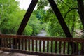 A gorgeous shot of the rushing water of the Big Creek river over a covered dark wood bridge with lush green trees