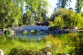 A gorgeous shot of the stone bridge with 3 circles over the green lake surrounded by lush green and autumn colored trees