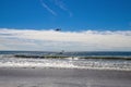 A gorgeous shot of the vast blue ocean water with waves breaking toward the beach with a man on a jet ski and a boat on the water Royalty Free Stock Photo