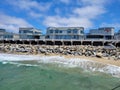 A gorgeous shot of the vast blue ocean water and the waves crashing into the rocks under the pier with a long wooden pier Royalty Free Stock Photo