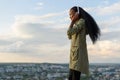 Gorgeous smiling african american girl listens music and relaxing. Blurred cityscape background. Outdoor portrait Royalty Free Stock Photo