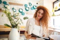 Gorgeous smiling redhead young lady standing in cafe reading Royalty Free Stock Photo