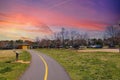 A gorgeous spring day in the park with a long smooth winding footpath with a yellow line surrounded by lush green grass