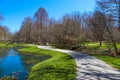 A gorgeous spring landscape in the garden with lush green grass, trees and plants and bare winter trees reflecting off the lake Royalty Free Stock Photo