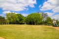 A gorgeous spring landscape in the garden with lush green trees, grass and plants with red flowers and blue sky with clouds Royalty Free Stock Photo