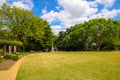 A gorgeous spring landscape in the garden with lush green trees, grass and plants with red flowers and blue sky with clouds Royalty Free Stock Photo