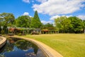 A gorgeous spring landscape in the garden with lush green trees, grass and plants with red flowers and blue sky with clouds