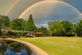 A gorgeous spring landscape in the garden with lush green trees, grass and plants with red flowers and blue sky with clouds Royalty Free Stock Photo