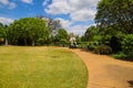 A gorgeous spring landscape in the garden with lush green trees, grass and plants with red flowers and blue sky with clouds Royalty Free Stock Photo