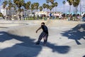 a gorgeous spring landscape at Venice Beach Skatepark at Venice Beach with young men riding skateboards and people watching Royalty Free Stock Photo